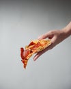 Traditional pepperoni pizza recipe, Italian cuisine concept. Close up on one piece of pizza in hand Royalty Free Stock Photo