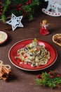 Traditional Polish Christmas dish, noodles with poppy seeds, raisins, candied fruits and sliced almonds on a red plate on a brown Royalty Free Stock Photo