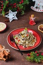 Traditional Polish Christmas dish, noodles with poppy seeds, raisins, candied fruits and sliced almonds on a red plate on a brown Royalty Free Stock Photo