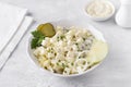 Traditional polish salad with apple, pickled cucumber, onion and mayonnaise on a light gray background