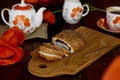 Traditional poppy seed bun with cup of tea and milk near poppies flowers and dishes with poppies ornaments. Delicious Royalty Free Stock Photo