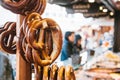 Traditional pretzels called Brezel hang on the stand against the background of a blurred street market and people on