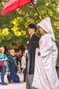 Traditional procession of a Japanese shinto wedding with a couple in kimono under an umbrella. Royalty Free Stock Photo