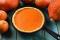 Traditional pumpkin pastry. Homemade bright colored pumpkin pie baked in cast iron pan on blue background