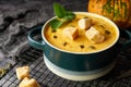 Traditional pumpkin soup puree with crackers, cream and seeds in a bowl, on a dark background