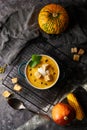 Traditional pumpkin soup puree with crackers, cream and seeds in a bowl, on a dark background