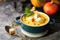 Traditional pumpkin soup puree with crackers, cream and seeds in a bowl, on a dark background