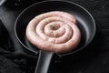 Traditional raw spiral pork sausages in cast iron frying pan  on black wooden table background Royalty Free Stock Photo
