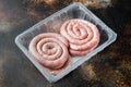 Traditional raw spiral pork sausages  on old dark rustic background  in plastic pack Royalty Free Stock Photo