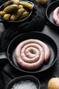 Traditional raw spiral pork sausages in cast iron frying pan  on black wooden table background Royalty Free Stock Photo