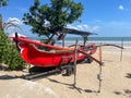 Traditional red banana boat sitting on the sand being used as a surf life saving vessel at Legian Beach Bali Royalty Free Stock Photo