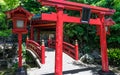 Traditional red Bridge, Lantern and Torii to japanese Jigoku Meguri Shinto Shrine framed by a green landscape. In Beppu, Oita