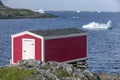Red fishing stage on coast, icebergs in bay, Newfoundland Royalty Free Stock Photo