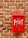 Traditional red postbox fixed on house brick wall by house entrance used for mail & letter delivery. Royalty Free Stock Photo