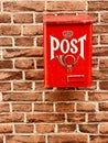 Traditional red postbox fixed on house brick wall by house entrance used for mail & letter delivery Royalty Free Stock Photo