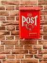 Traditional red postbox fixed on house brick wall by house entrance used for mail & letter delivery. Royalty Free Stock Photo