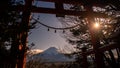 A traditional red torii gate and the Fuji mountain with snow cover at sunset