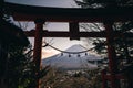 A traditional red torii gate and the Fuji mountain with snow cover at sunset