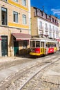 Traditional red and yellow tram in a cobblestoned street of Lisbon