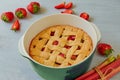 Traditional rhubarb strawberry pie in the baking dish on the gray kitchen table. Veggie tart decorated with organic strawberries Royalty Free Stock Photo