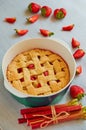 Traditional rhubarb strawberry pie in the baking dish on the gray kitchen table. Veggie tart decorated with strawberries Royalty Free Stock Photo