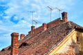 Traditional roofs in Sibiu, Romania, with eye shaped windows, brick chimneys and old TV antennas on top, on a bright day. Royalty Free Stock Photo