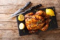 Traditional rotisserie chicken served with lemon closeup on a slate board on a table. Horizontal top view