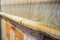 A traditional rug being woven on a carpet vertical loom, showing wool pile under tension, foundation, warp and weft Royalty Free Stock Photo