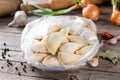 Traditional Russian dumplings, ravioli, meat dumplings on a wooden table. Rolling pin, napkin, garlic, onion, bay leaf and spices Royalty Free Stock Photo