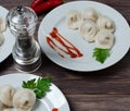 Traditional Russian dumplings, ravioli, pelmeni on a white plate with red sauce and parsley. Dark wooden background Royalty Free Stock Photo