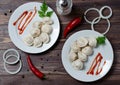 Traditional Russian dumplings, ravioli, pelmeni on a white plate with red sauce and parsley. Dark wooden background. Onion rings, Royalty Free Stock Photo