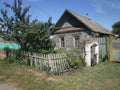 Traditional Russian landscape with a village house, shutters, landscape in the background and trees with grass. Royalty Free Stock Photo