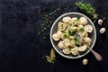 Traditional russian pelmeni, ravioli, dumplings with meat on black concrete background. Parsley, quail eggs, pepper