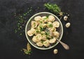 Traditional russian pelmeni, ravioli, dumplings with meat on black concrete background. Parsley, quail eggs, pepper