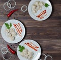 Traditional Russian pelmeni, ravioli, dumplings on a white plate with red sauce and parsley. Dark wooden background. Onion rings, Royalty Free Stock Photo