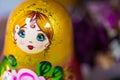 A traditional Russian toy, Matryoshka, bright babushka doll, stacking doll, nesting doll with a beautiful face, in gold, green, ye