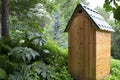 Traditional rustic wooden toilet with a metal roof in a park or garden Royalty Free Stock Photo