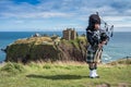 Traditional scottish bagpiper in full dress code at Dunnottar Castle Royalty Free Stock Photo