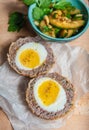 Traditional Scottish meat cutlet with boiled eggs, cucumber and parsley on cutting board