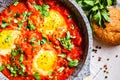 Traditional shakshuka in pan. Fried eggs in tomato sauce with herbs, top view
