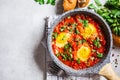 Traditional shakshuka in pan. Fried eggs in tomato sauce with herbs, top view