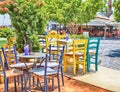 Traditional sidewalk greek cafe with multicolored tables and ch Royalty Free Stock Photo