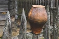 Traditional Slavic decor in village. Clay vintage terra cotta water pot on wooden fence at countryside. Rural landscapes