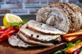 Traditional sliced baked pork garnished with herbs, lemon carrots and spices, prepared for serving on the festive table