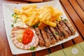 Traditional slovenian cuisine, meat kebab - chevapchichi - with french fries. Selective focus Royalty Free Stock Photo