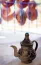 Traditional small moroccan teapot with lid and plates i background