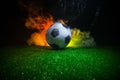 Traditional soccer ball on soccer field. Close up view of soccer ball (football) on green grass with dark toned foggy background.