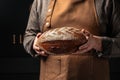 Traditional sourdough bread in baker hands. bakery products on a dark background