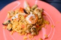 Traditional Spanish dish Paella with meat, rice , seafood on pink plate