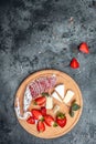 Traditional Spanish Fuet thin dried sausage with Camembert cheese, strawberries and glass rose wine on dark background. vertical Royalty Free Stock Photo